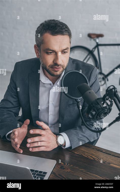 Serious Radio Host Gesturing While Speaking In Microphone At Workplace