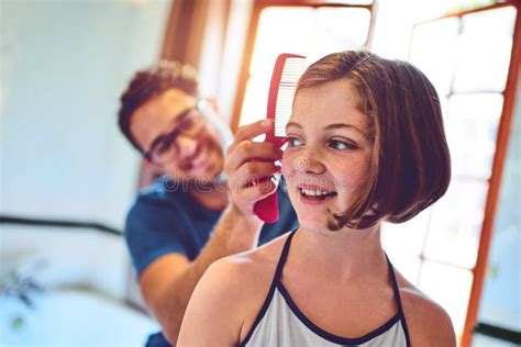 Dad Makes The Prettiest Hairstyles A Father Combing His Little Daughters Hair At Home Stock