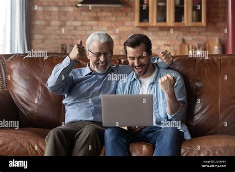 Overjoyed Mature Father And Son Celebrating Success Using Laptop Stock Photo Alamy