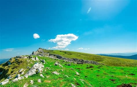 Landscape of green grass and rock hill in spring with beautiful blue ...