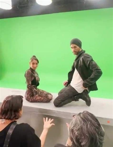 Two People Are Sitting On A Ledge In Front Of A Green Screen And One