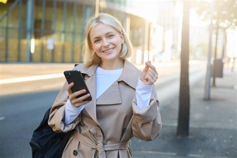 Premium Photo Portrait Of Cute Blonde Woman Smiling Standing On Street With Mobile Phone