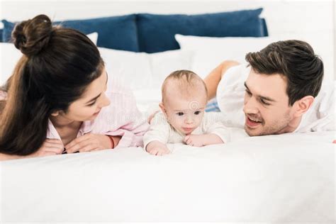 Portrait of Young Parents and Little Baby Lying on Bed Together Stock ...