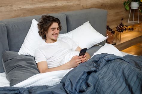 Premium Photo Handsome Young Man In Pajamas Using A Cellphone While