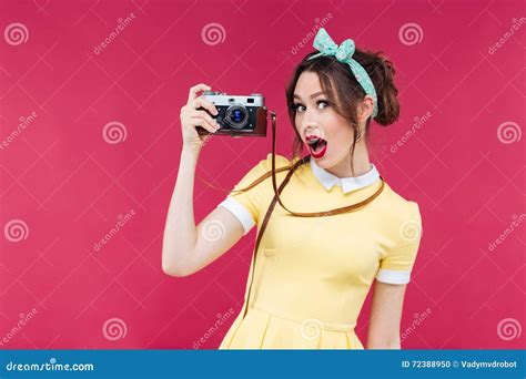 Amazed Beautiful Pinup Girl In Yellow Dress Holding Old Camera Stock