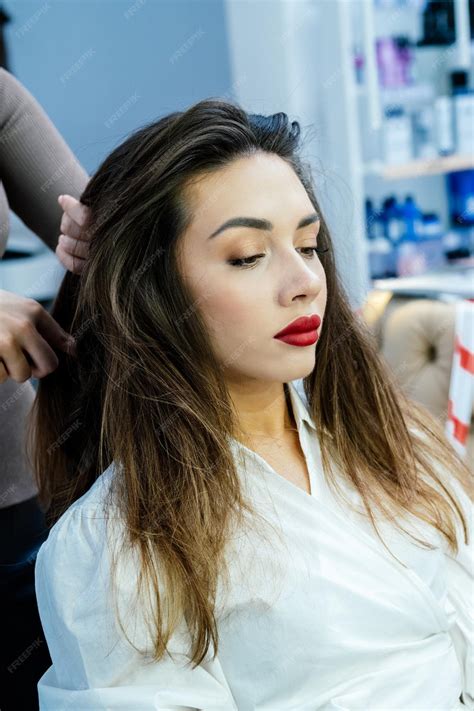 Premium Photo | Beautiful brunette woman curls her hair with a curling ...