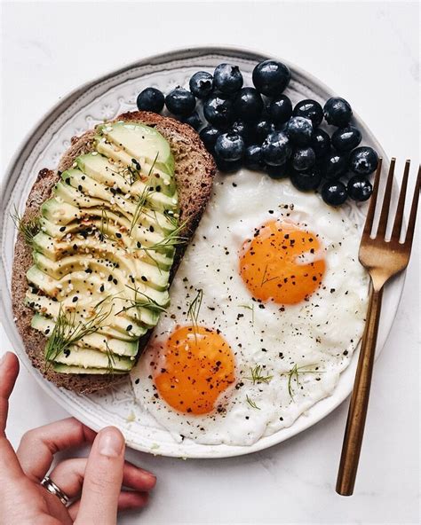 A Plate With Eggs Avocado And Blueberries On It Next To A Fork