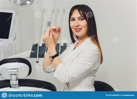 Portrait Of Attractive Smiling Female Dentist With Hands Folded Stock