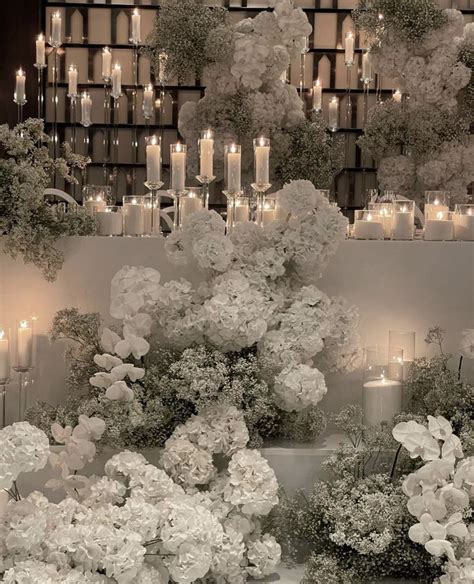 White Flowers And Candles Are Arranged In Front Of A Wall