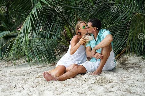 De Jongelui Koppelt Zitten De Vrouw En De Man Op Het Strand En Zullen Selfies Gekleed In