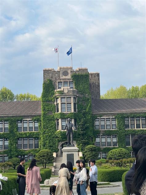 People Standing In Front Of A Building With Ivy Growing On It