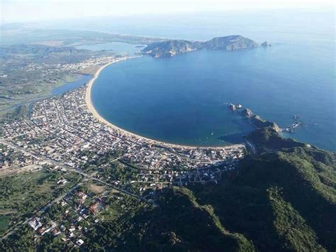 an aerial view of a small town by the ocean with mountains in the back ...