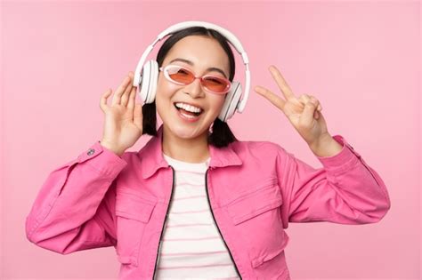 Dançando elegante garota asiática ouvindo música em fones de ouvido