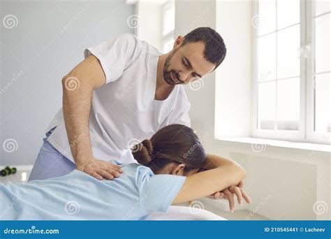 Osteopath In Medical Uniform Fixing Woman Patients Shoulder And Back