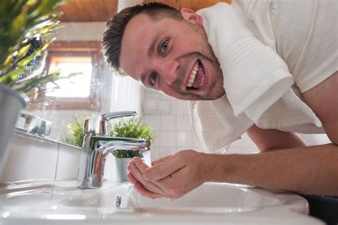 Caucasian Man Washing Face In A Wash Basin In White Washroom Stock