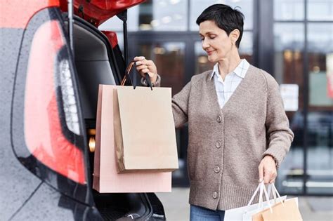 Premium Photo Smiling Woman Putting Shopping Bags On Car Trunk