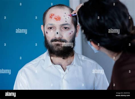 Wife Helping Man Prepare For Halloween Dressing Him As Devil