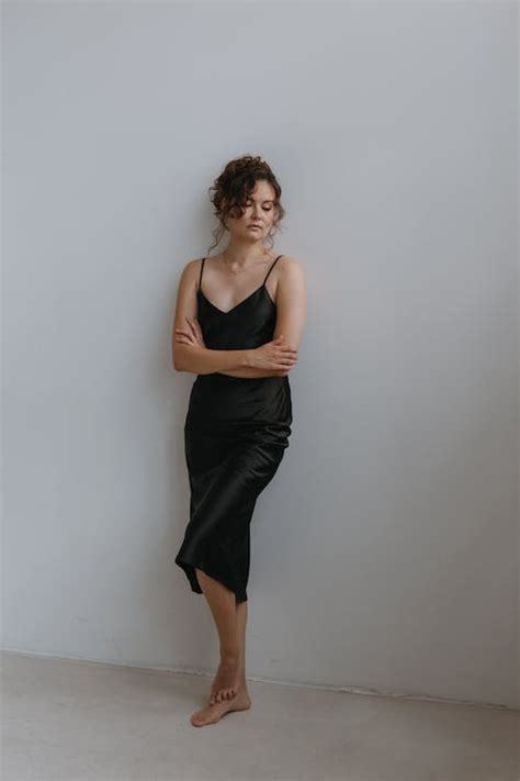 Barefoot Woman in Black Dress Standing under White Wall · Free Stock Photo