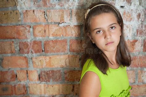 Menina Triste Na Frente De Uma Parede De Tijolo Imagem De Stock