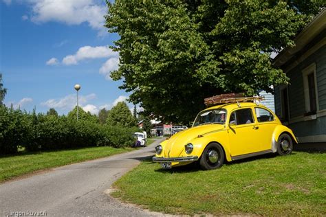 An Old Yellow Car Parked In Front Of A House On The Side Of A Road