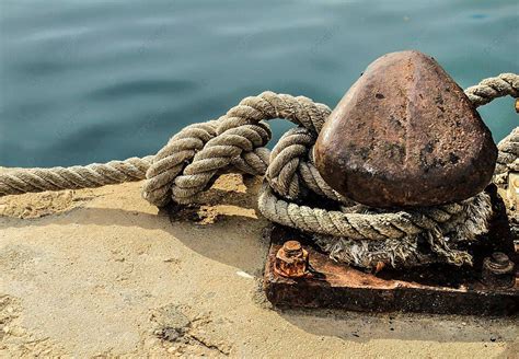 Tethered Rope On Weathered Docking Bollard In Port Photo Background And