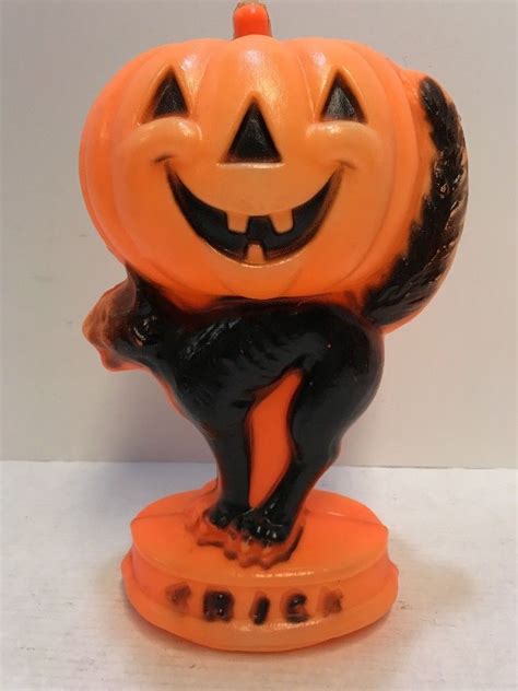 An Orange And Black Cat Figurine With A Jack O Lantern On Its Head