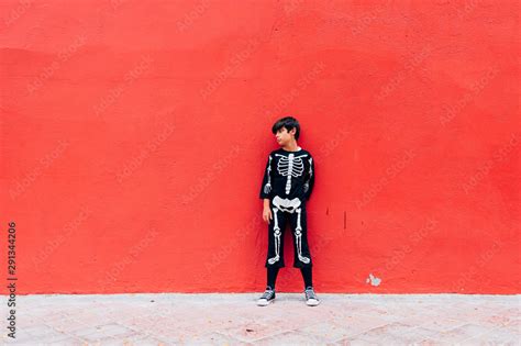 Boy in skeleton costume standing in street on the red background Stock ...