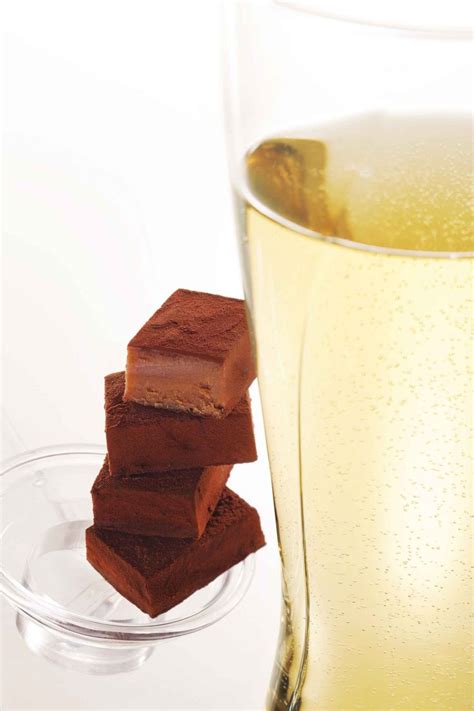 Three Pieces Of Brownies Sitting Next To A Glass Of Liquid On A White Table