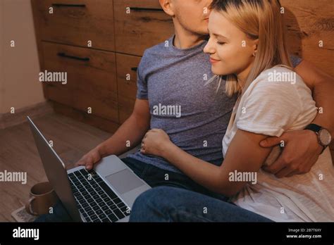 Jolie femme blonde embrassant son amant tout en étant assise dans la cuisine sur le sol et en