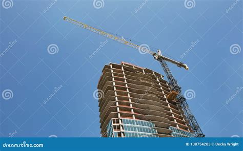 A Crane Rissing Above A New High Rise Building Under Construction