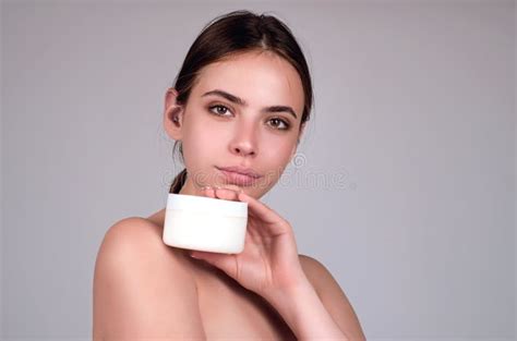 Beauty Portrait Of A Beautiful Half Naked Woman Applying Face Cream Isolated On Studio