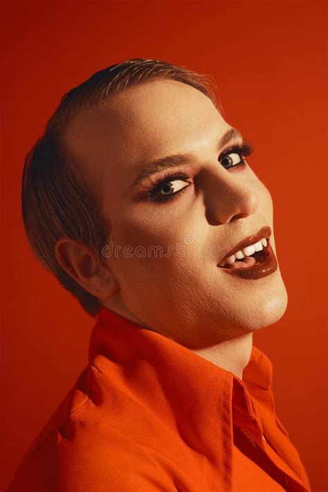 Retrato De Un Joven Gay Con Un Maquillaje Brillante Posando Sobre Un Fondo De Estudio Rojo Foto