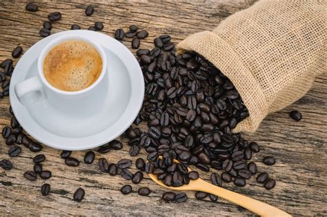 Tasse à Café Et Grains De Café Torréfiés Dans Un Sac Sur Un Plancher En Bois Photo Premium