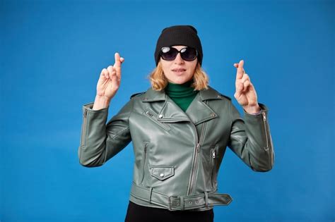 Jolie jeune femme blonde en veste verte posant isolé sur fond bleu Concept de mode de vie des