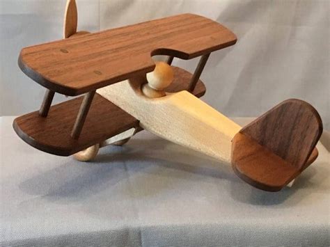 A Wooden Toy Airplane Sitting On Top Of A White Sheet