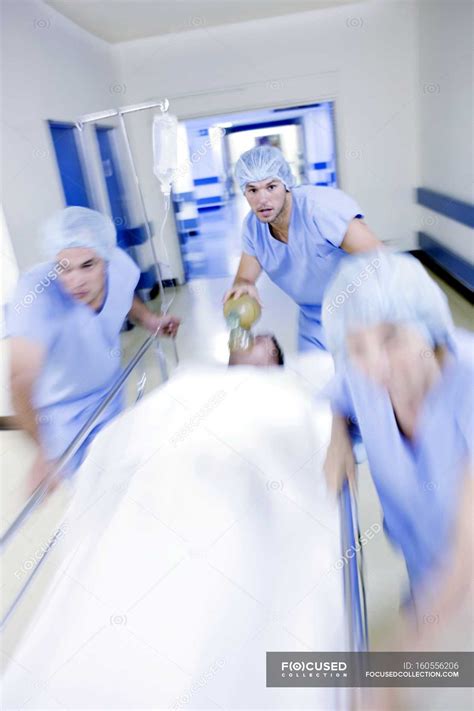 Emergency team pushing hospital gurney with patient in corridor