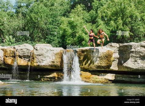 Caucasian Couple Jumping Off Rocks Near Waterfalls Stock Photo Alamy