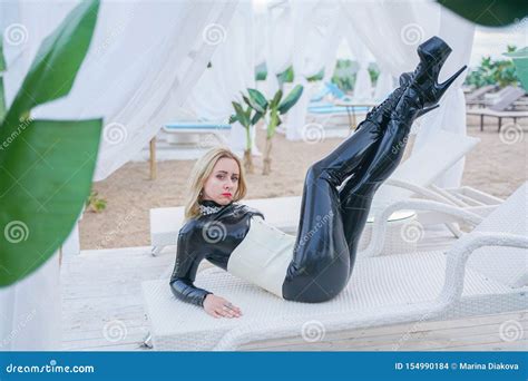 Jeune Fille Blonde Mince D Esclavage Dans La Combinaison Pantalon Noire De Latex Avec Le Corset