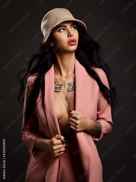 Sexy Pretty Brunette Woman With Tattoo On Body In Pink Silky Suit With Deep Neckline And Naked