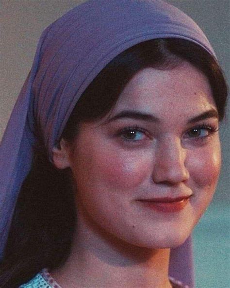 A Woman Wearing A Purple Turban And Smiling At The Camera With Her Eyes