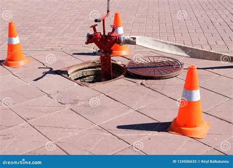 A Large Red Metal Fire Hydrant With Hoses And Sleeves Connected To The