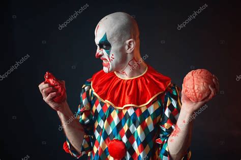 El maldito payaso loco sostiene el corazón y el cerebro humanos Hombre