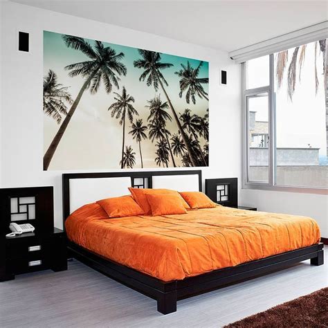 An Orange Bed In A White Bedroom With Palm Trees Painted On The Wall