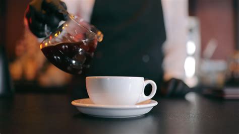 Pouring Black Coffee In Cup Waiter Pouring Coffee Into A White Cup In