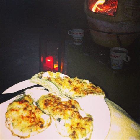 Some Food Is Sitting On A White Plate Near A Fire Place With Two Mugs