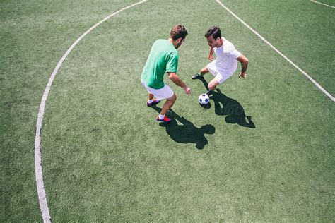 Two Men Playing Soccer On A Field During A Match By Stocksy