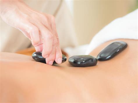 An Expert Masseuse At A Spa Salon Puts Hot Stone On The Back Of An Asian Woman To Relieve