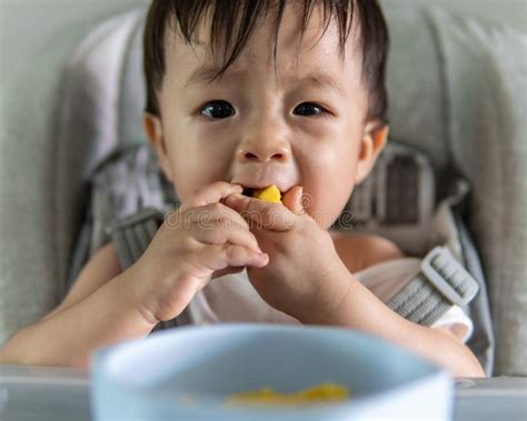 Happy Asian Chinese Baby Boy Siting On Baby Chair Enjoying His Lunch