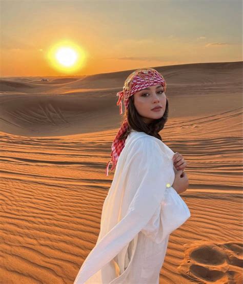 A Woman Standing In The Desert At Sunset