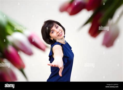An Adult Brunette In A Blue Blouse White Background With Bright Red Juicy Tulips Stock Photo Alamy